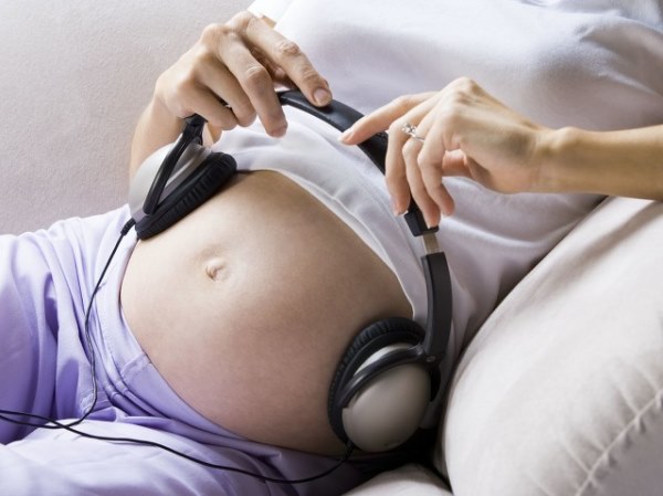 怀孕的女人坐在肚子上戴着耳机.jpg